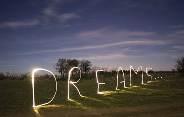 Evening landscape with the word "Dreams" spelled in white light